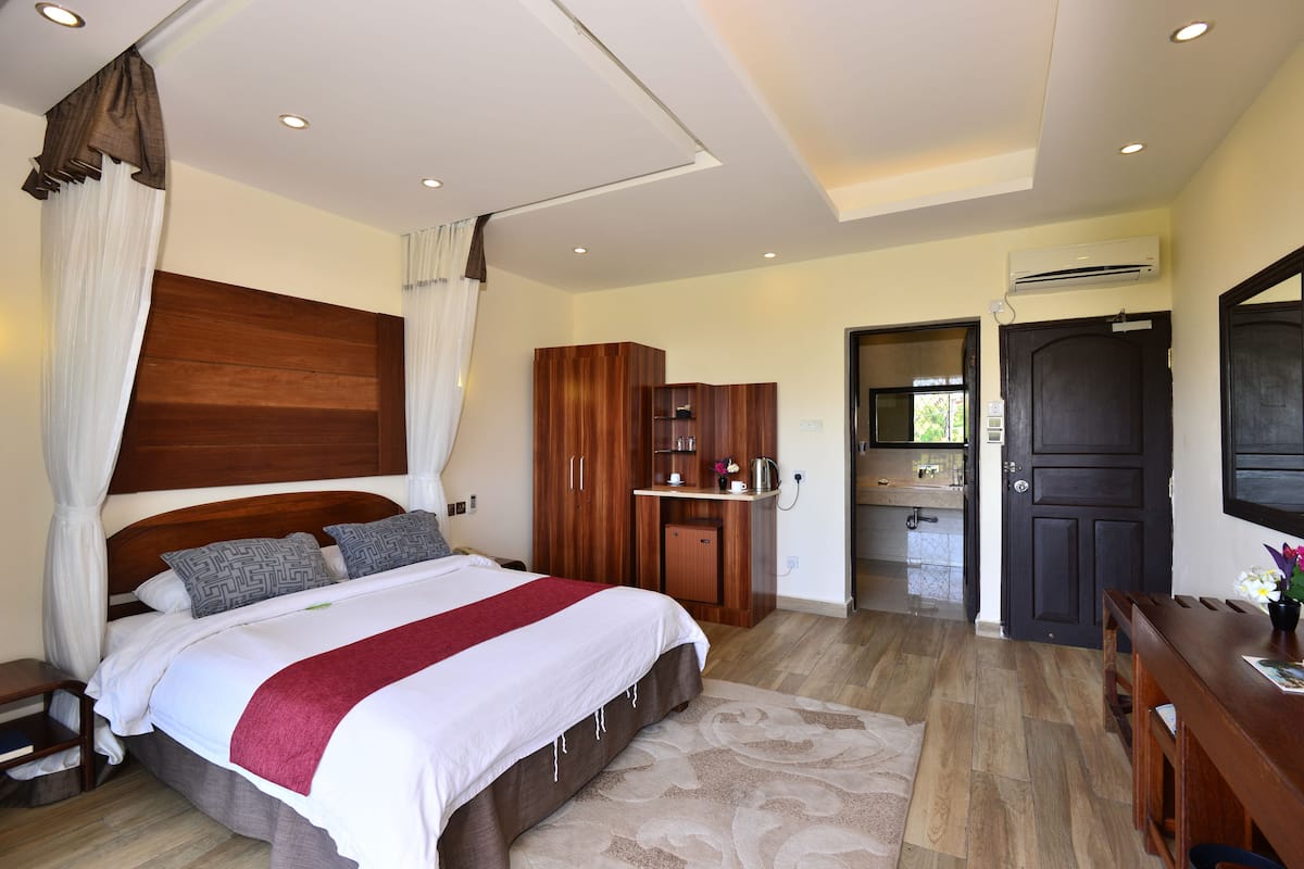 Un dormitorio con una cama grande, un armario de madera y un escritorio con una silla.