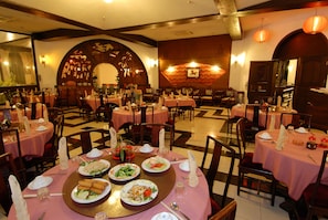 A restaurant with round tables covered in pink tablecloths, each set with plates, cutlery, and napkins. - Baobab Holiday Resort (Mombasa)