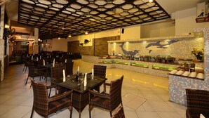A restaurant with a unique hexagonal ceiling design, a central island with a mosaic backsplash, and wicker furniture. - Baobab Holiday Resort (Mombasa)