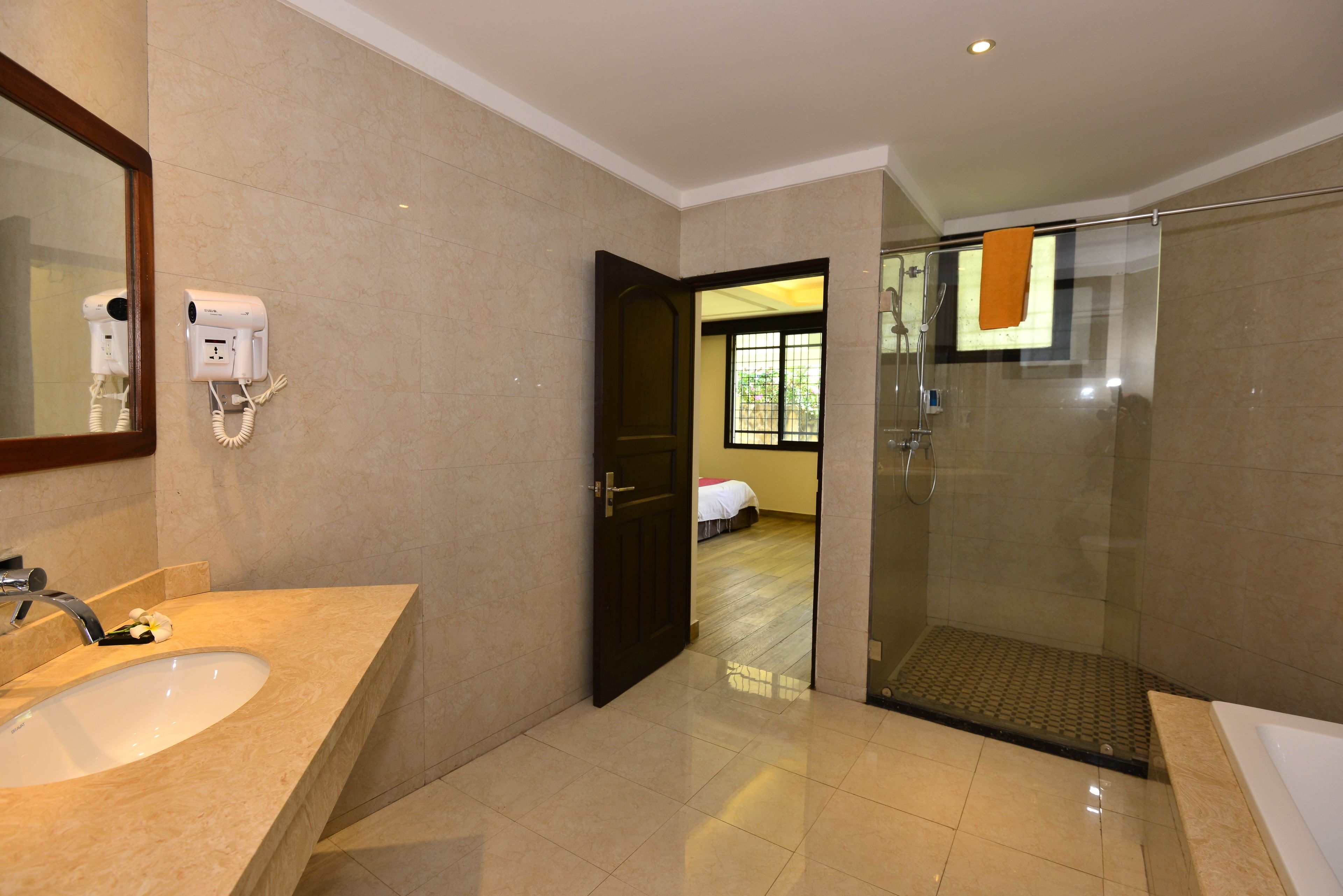 A modern bathroom with a large sink, a hairdryer, and a glass shower enclosure.