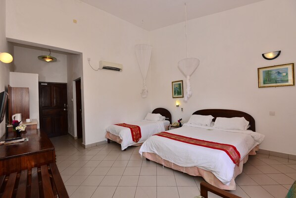 A hotel room with two beds, a wooden desk, and a dining table.
