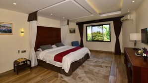 A modern hotel room with a large bed, a desk, a TV, and a window with a view of greenery. - Baobab Holiday Resort (Mombasa)