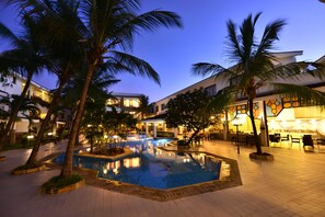 A pool area with palm trees, a bar, and outdoor seating.