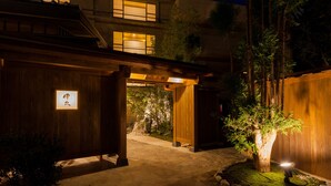 Un bâtiment traditionnel japonais, doté d’une entrée en bois et d’un petit arbre au centre.