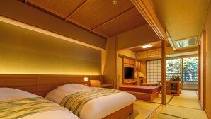 Une chambre de style japonais traditionnel, dotée de deux lits, d’une télévision et d’une porte coulissante donnant sur un balcon.