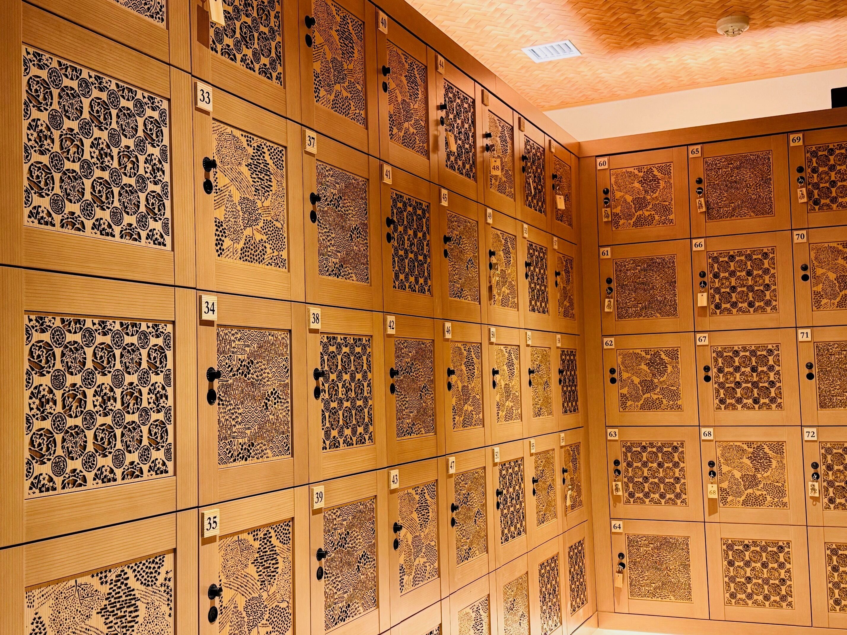 A row of wooden lockers with intricate designs and numbered tags.