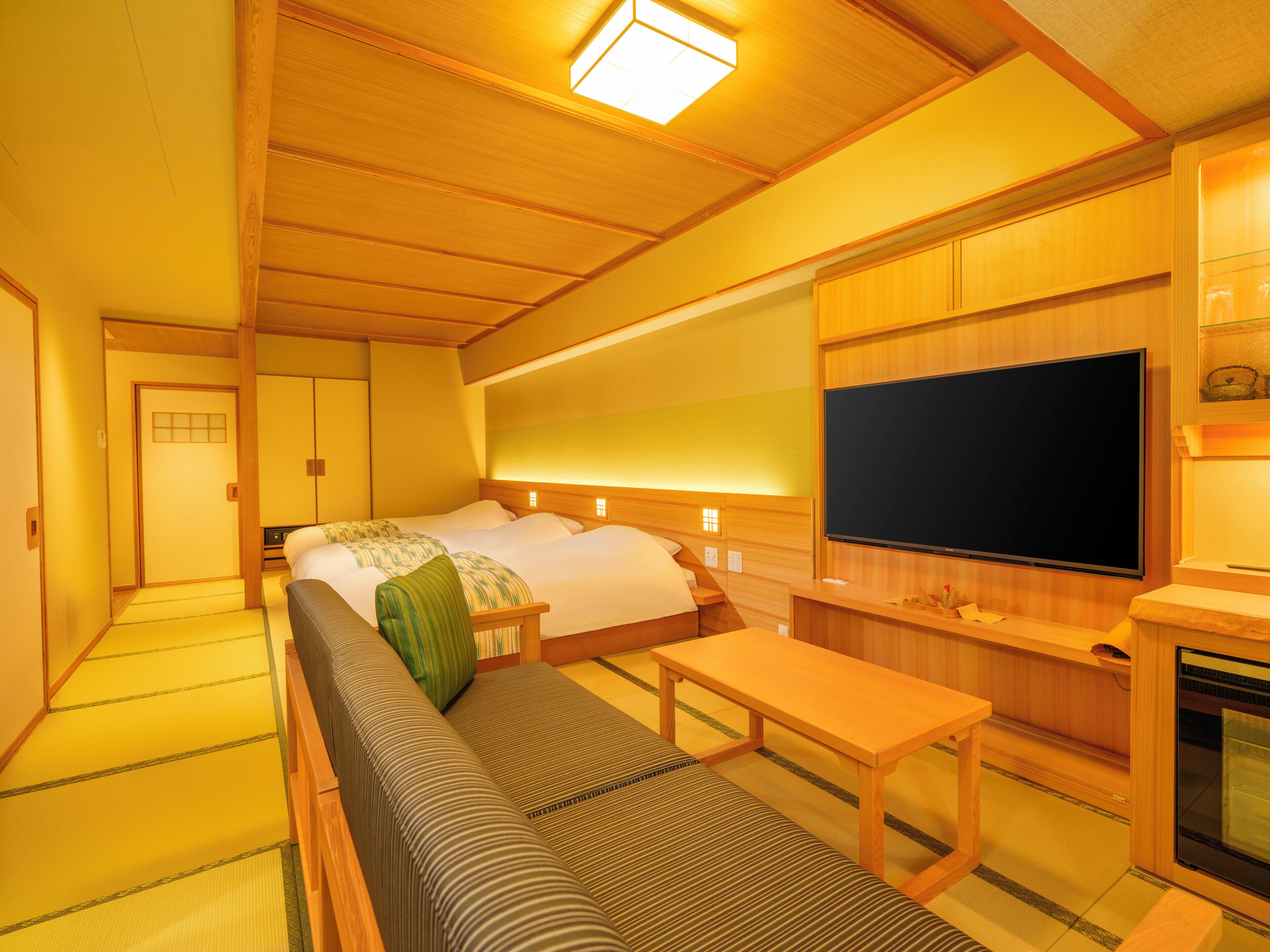 A traditional Japanese-style room with tatami flooring, a futon bed, a television, and a small table.