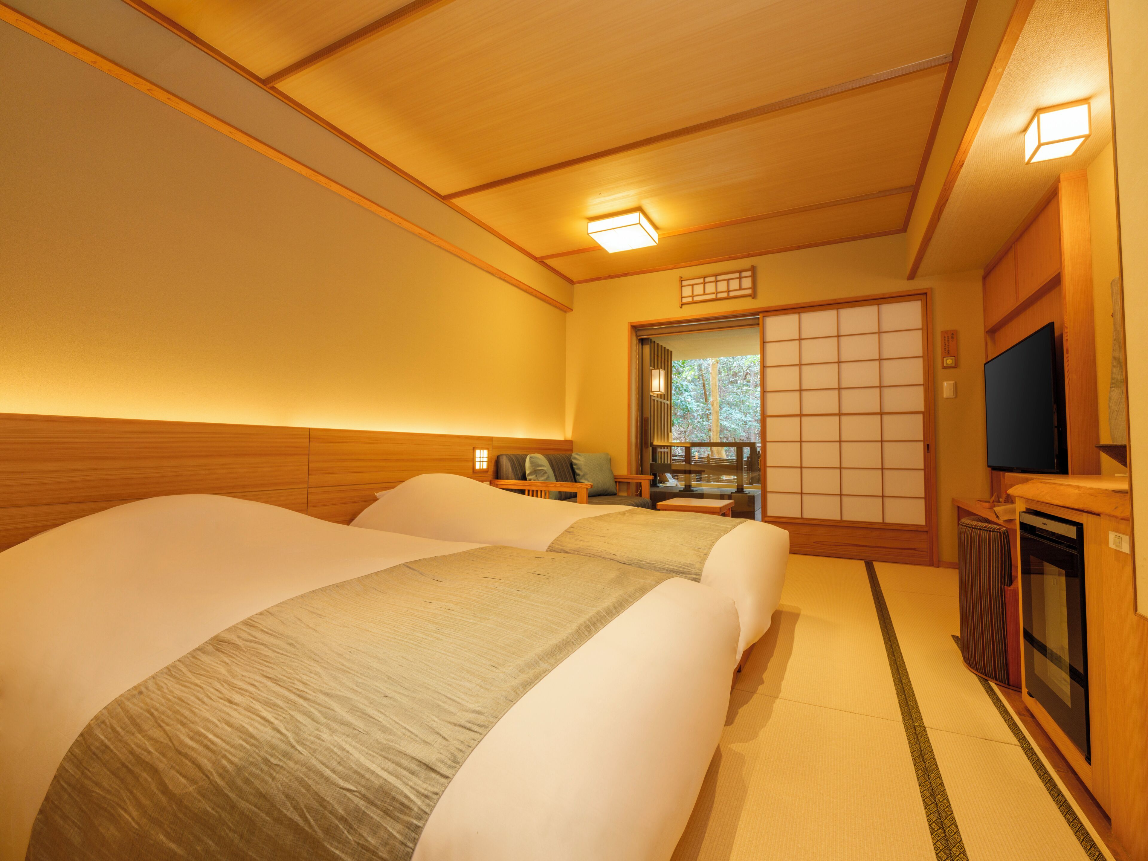 A hotel room with two beds, a TV, a sliding door, and a view of the outdoors.