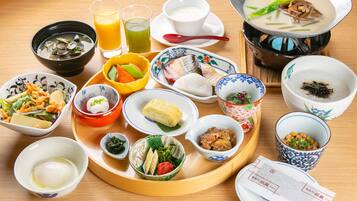 A variety of Japanese dishes on a wooden table, including a hot pot, bowls of soup, and plates of sashimi.