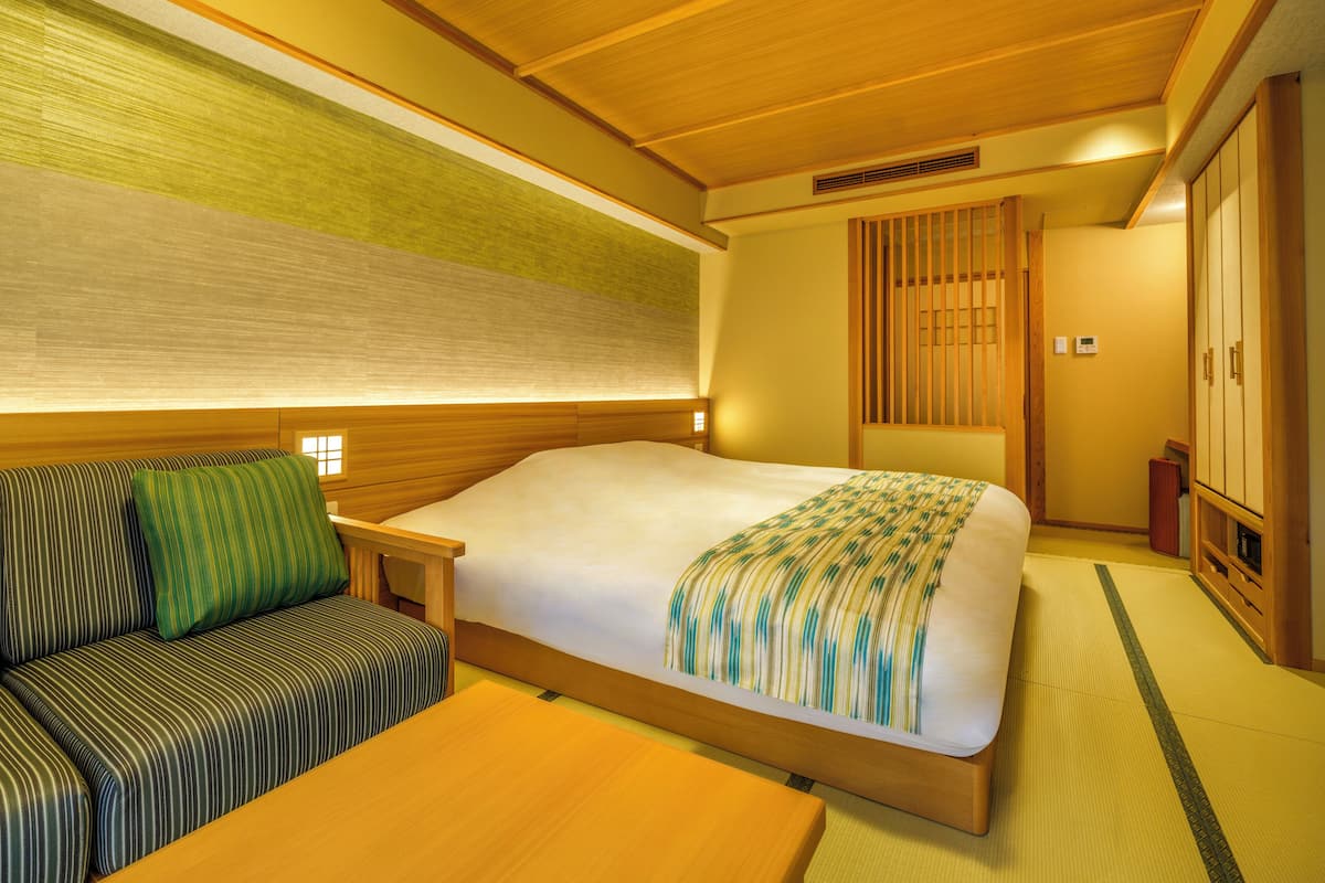 A room with a bed, a sofa, a wooden table, and a wardrobe.