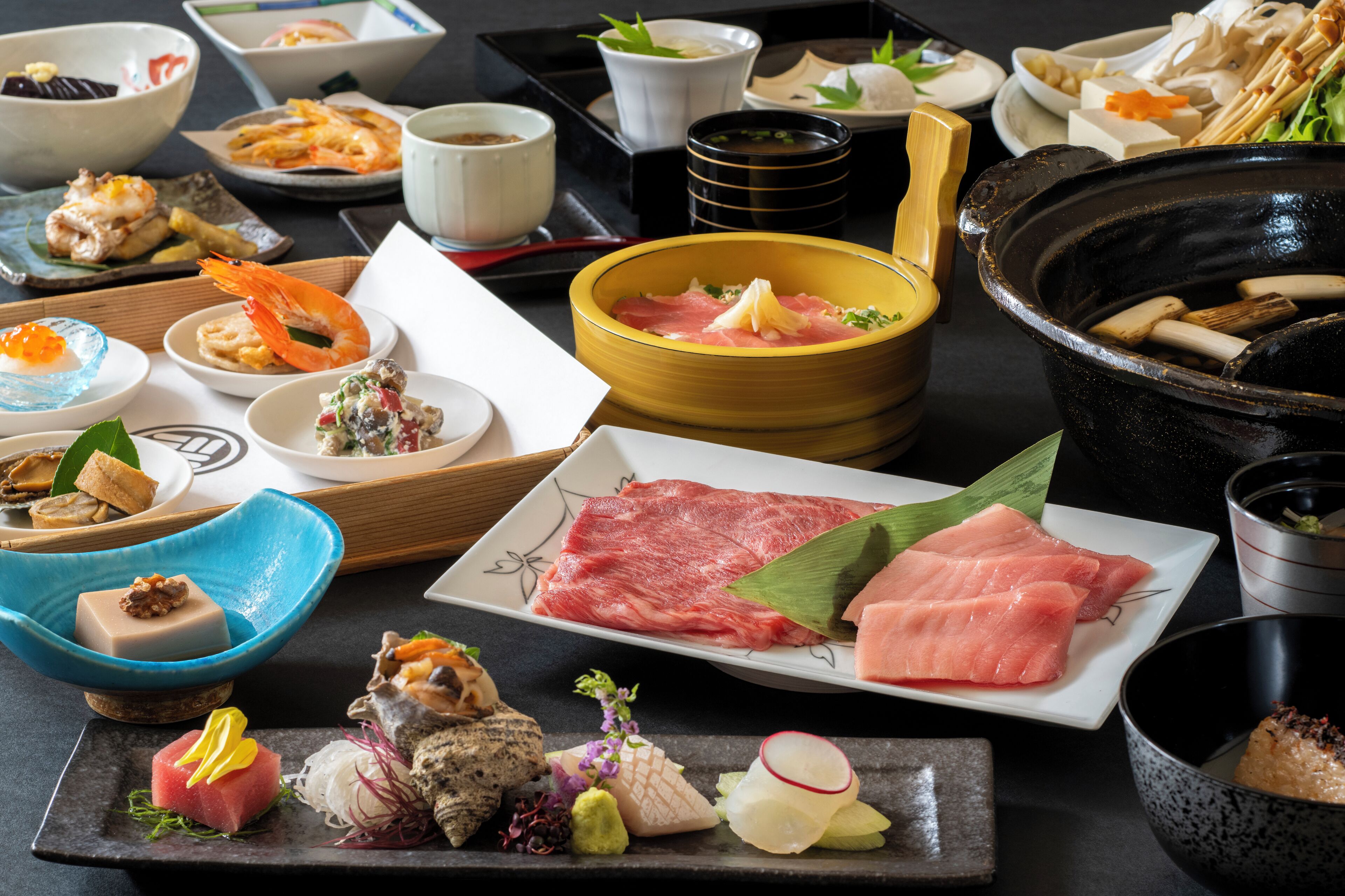A variety of sushi dishes and other Japanese cuisine on a table.