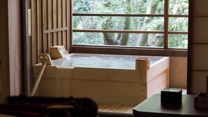 Un onsen japonais traditionnel, avec une porte coulissante en bois, un banc en bois et une vue sur la verdure environnante.