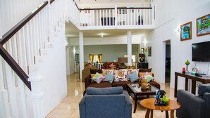 Ein geräumiges Wohnzimmer mit hoher Decke, einer Treppe und einem Balkon.