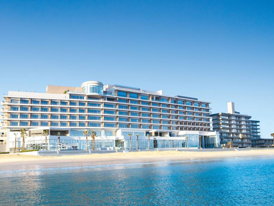 A large hotel with multiple floors, a beach view, and a pool.