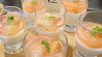 Varios vasos con un postre en capas, cubitos de hielo y una hoja verde, probablemente perejil, sobre una superficie de madera.