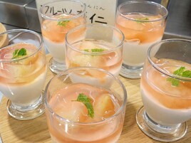 Varios vasos con un postre en capas, cubitos de hielo y una hoja verde, probablemente perejil, sobre una superficie de madera.