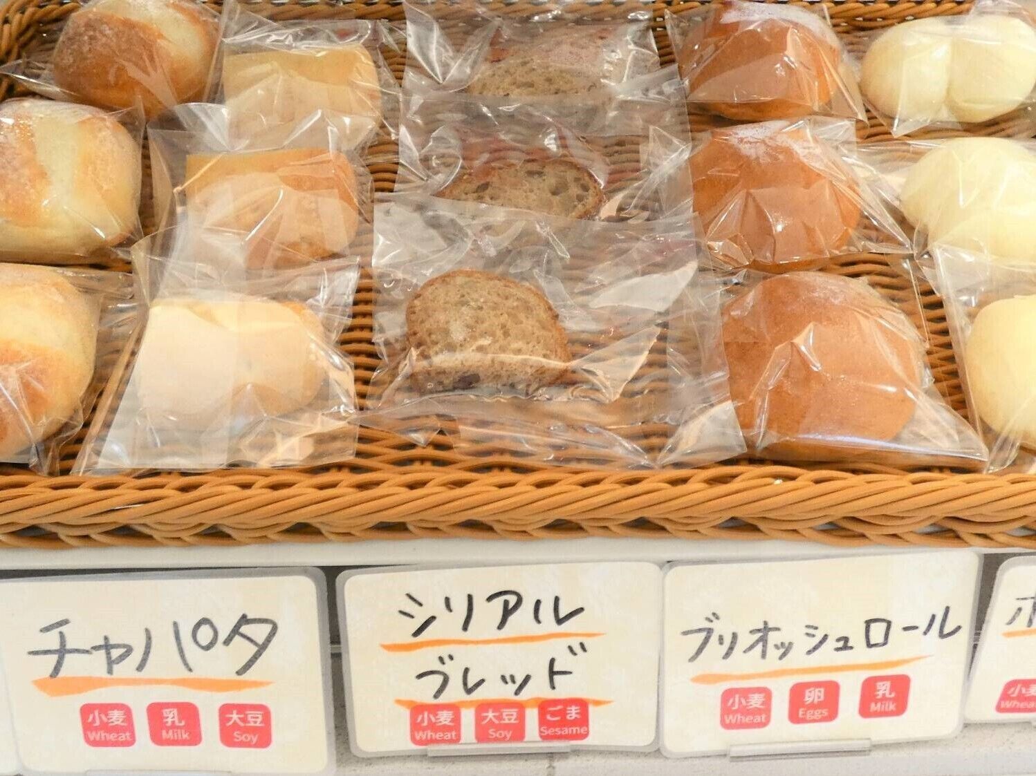 A basket of various packaged bread items, each labeled with different ingredients like wheat, milk, and soy.