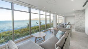 A modern lounge area with large windows offering a view of the sea and mountains. - Karatsu Seaside Hotel (Karatsu)