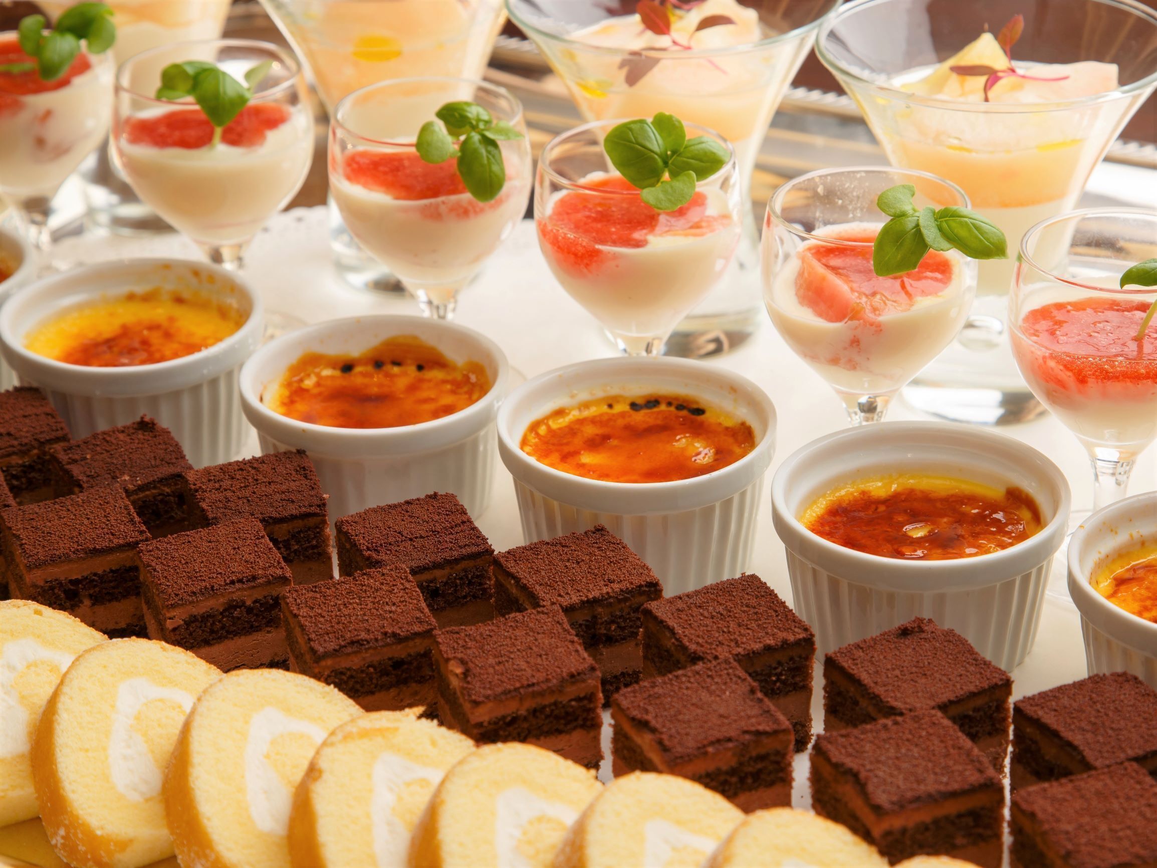 A variety of desserts including chocolate brownies and cream-based dishes, likely served at a buffet or event.