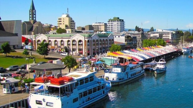 Una zona costera con barcos amarrados, una iglesia y una hilera de edificios de colores.