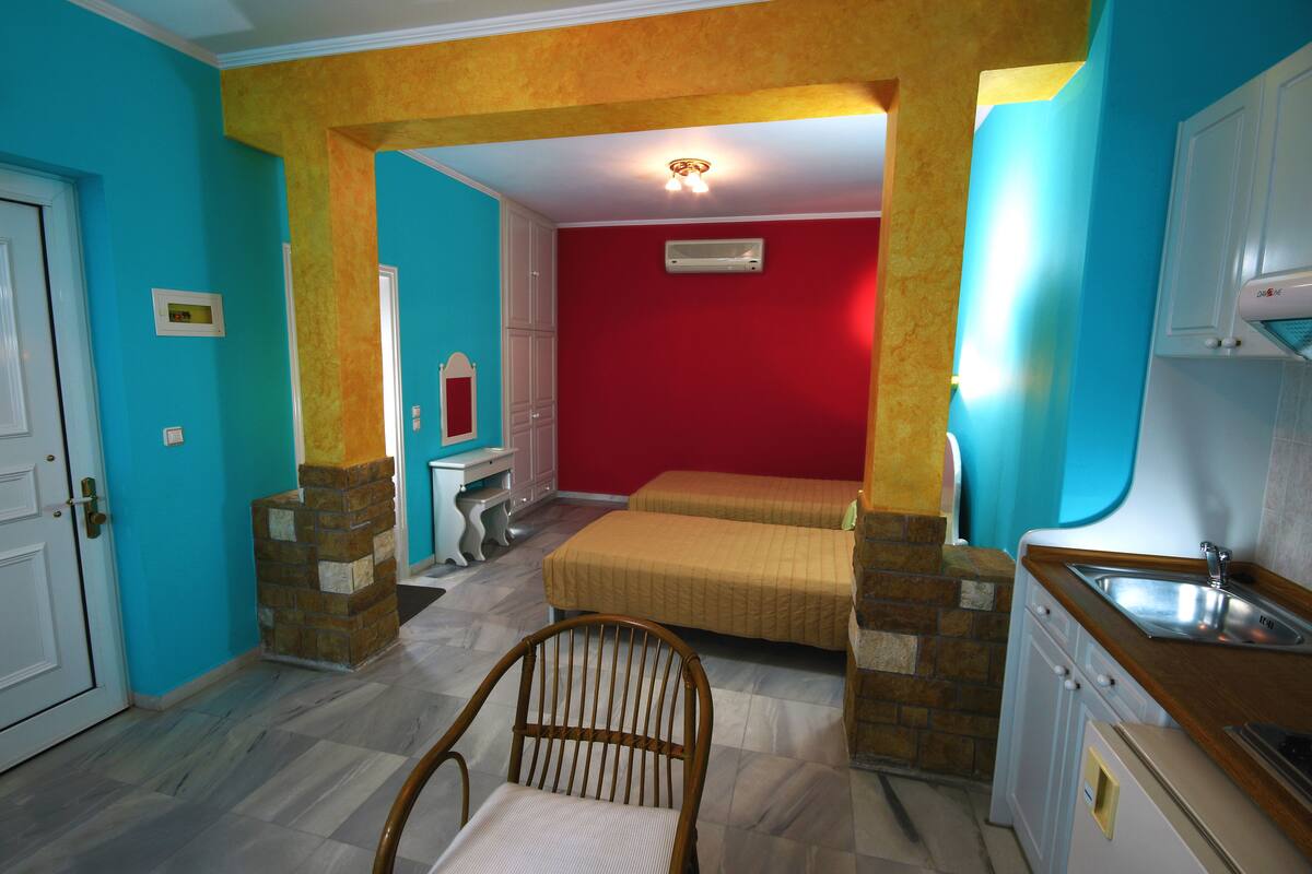 Ein kleines Zimmer mit einer Küchenzeile, einem Bett und einem Stuhl.