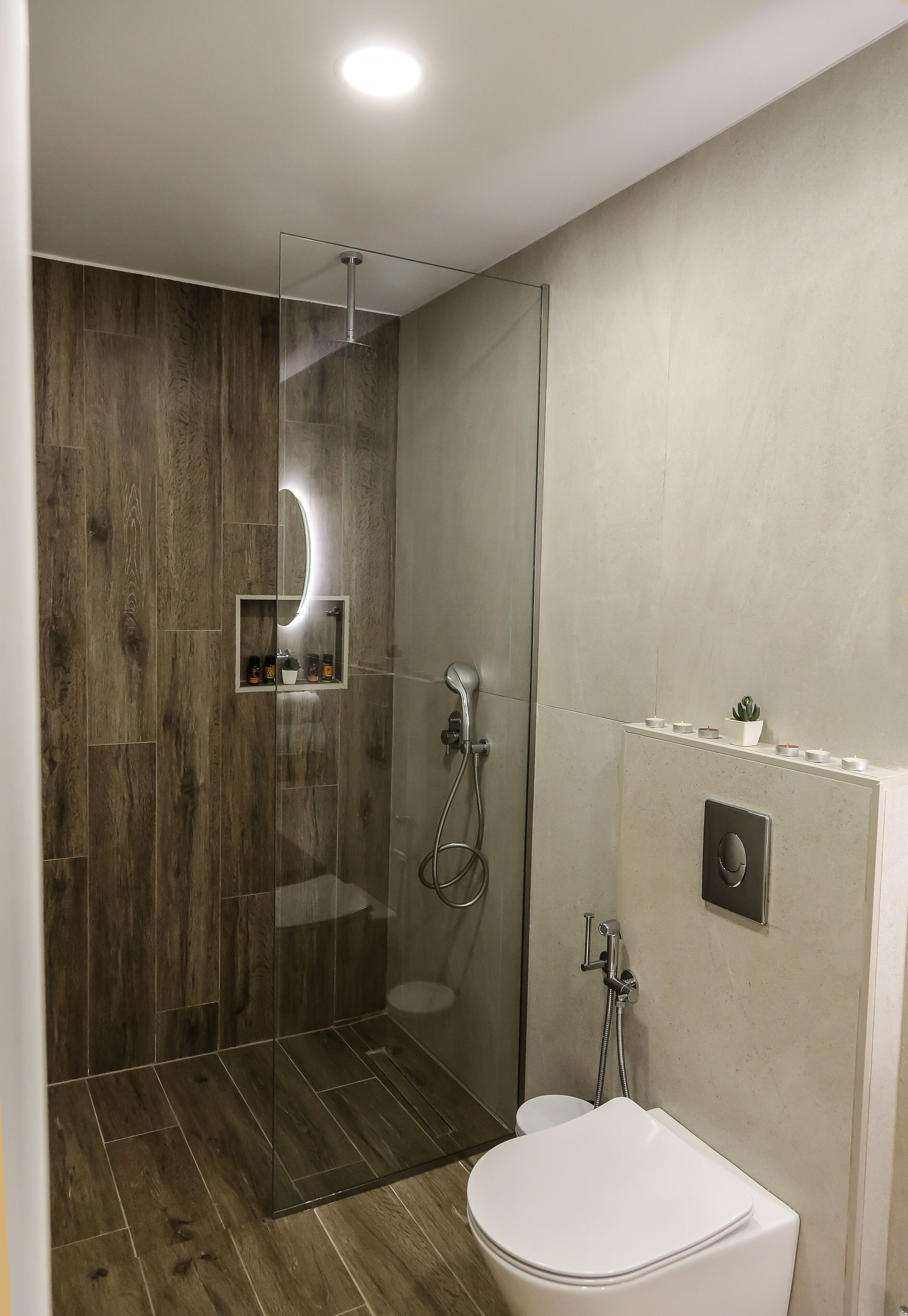 A modern bathroom with a glass-enclosed shower, a toilet, and a built-in sink.
