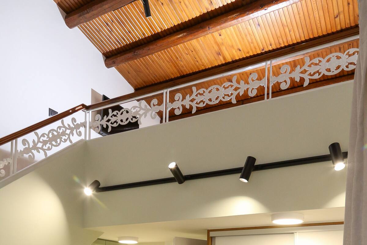 Eine moderne Küche mit grünen Schränken, einem Holzespeisetisch und einer Treppe mit dekorativer Geländer.