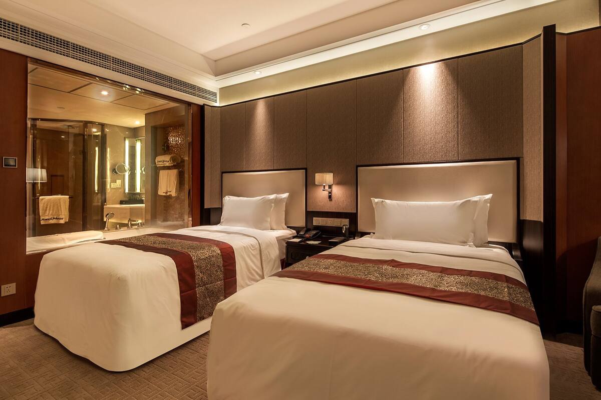 Habitació d'hotel amb dos llits, un mirall gran, un tocador amb un rentapins i un telèfon.