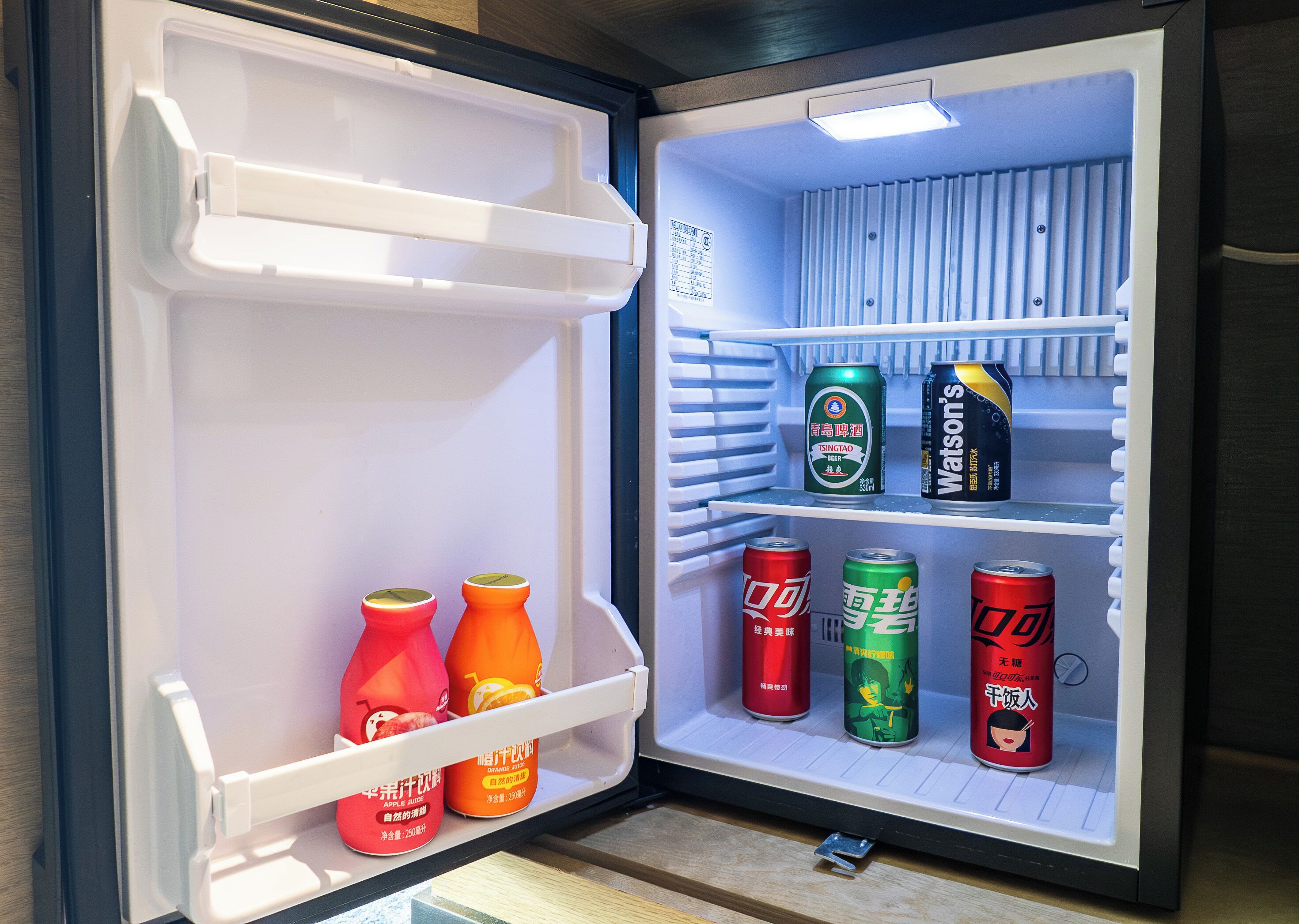 A mini-fridge with beverages and a can of beer.