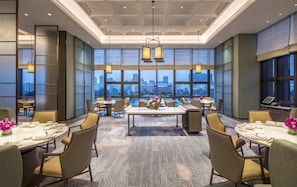 Un comedor espacioso con techos altos, ventanas amplias que ofrecen vistas a la ciudad e iluminación moderna.