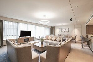 A modern living room with a flat-screen TV, a sofa, a coffee table, and a dining area with chairs and a table. - DoubleTree by Hilton Hotel Shenzhen Longhua (Shenzhen)