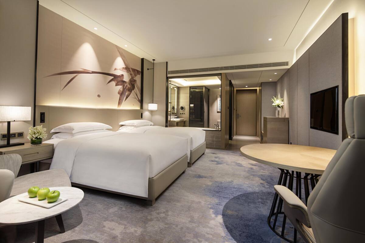 A modern hotel room with a large bed, a desk, and a seating area.