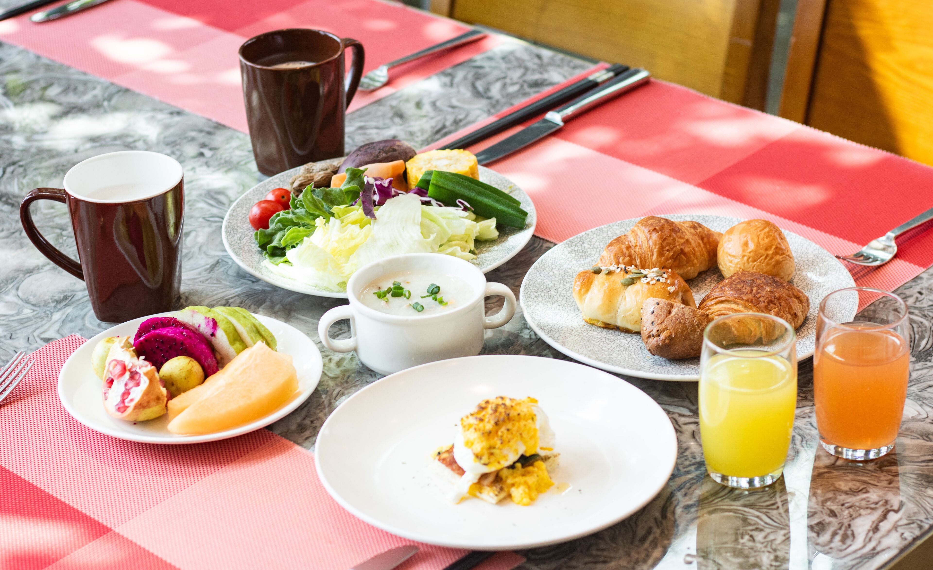 A breakfast table with plates of food, a coffee mug, and glasses of orange juice.