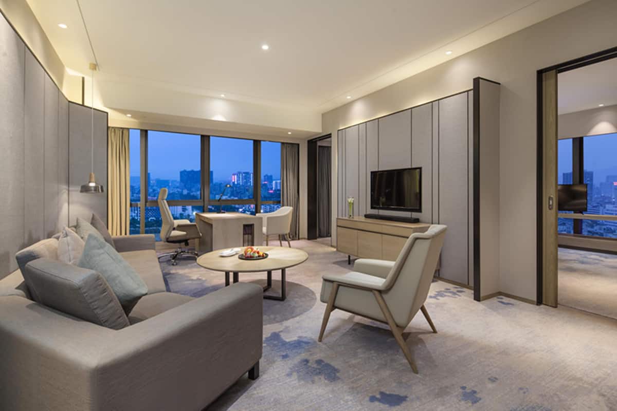 A modern living room with a sofa, chairs, a coffee table, and a TV.