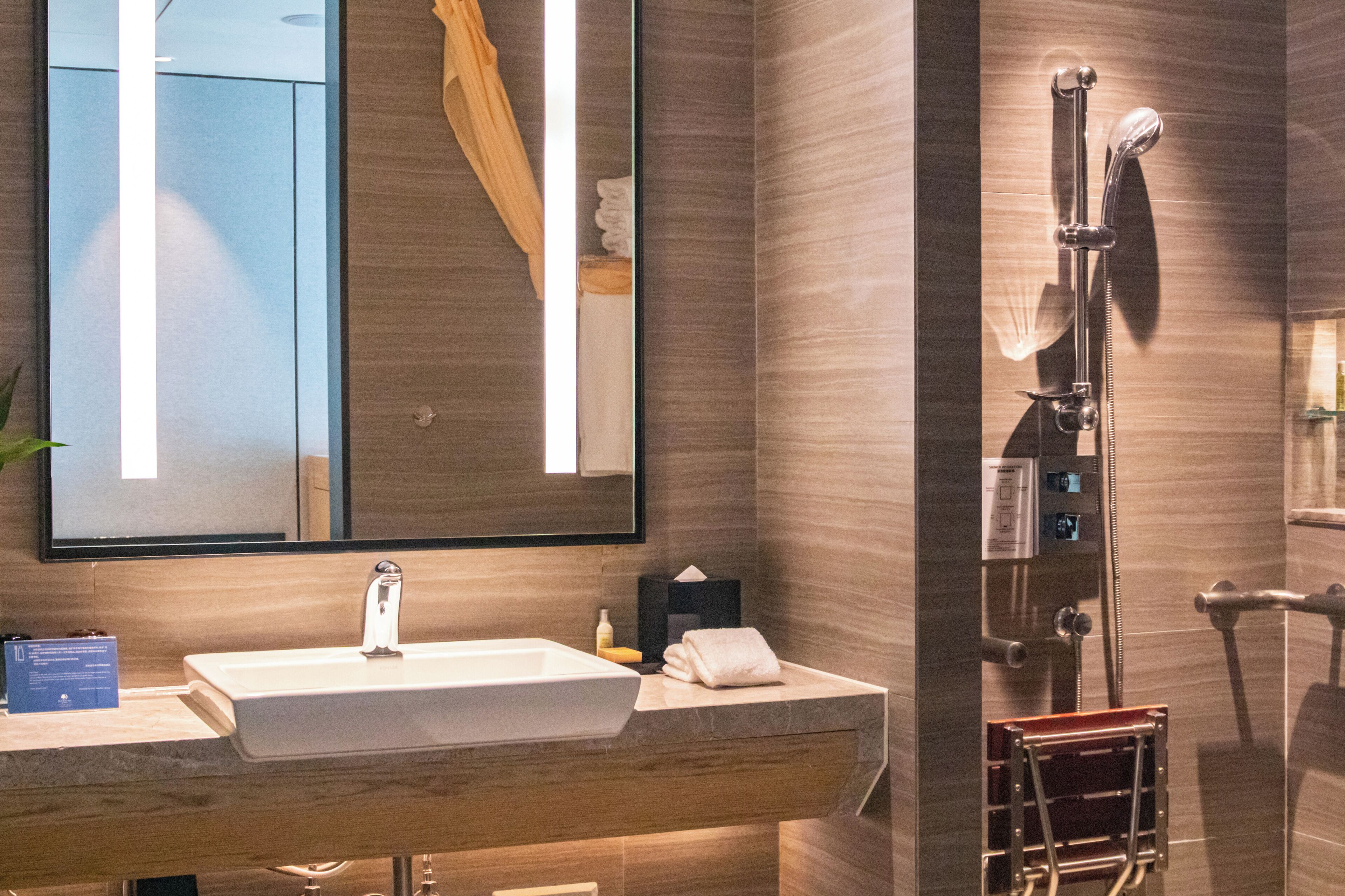 A modern bathroom with a large mirror, a sink, and a shower area.