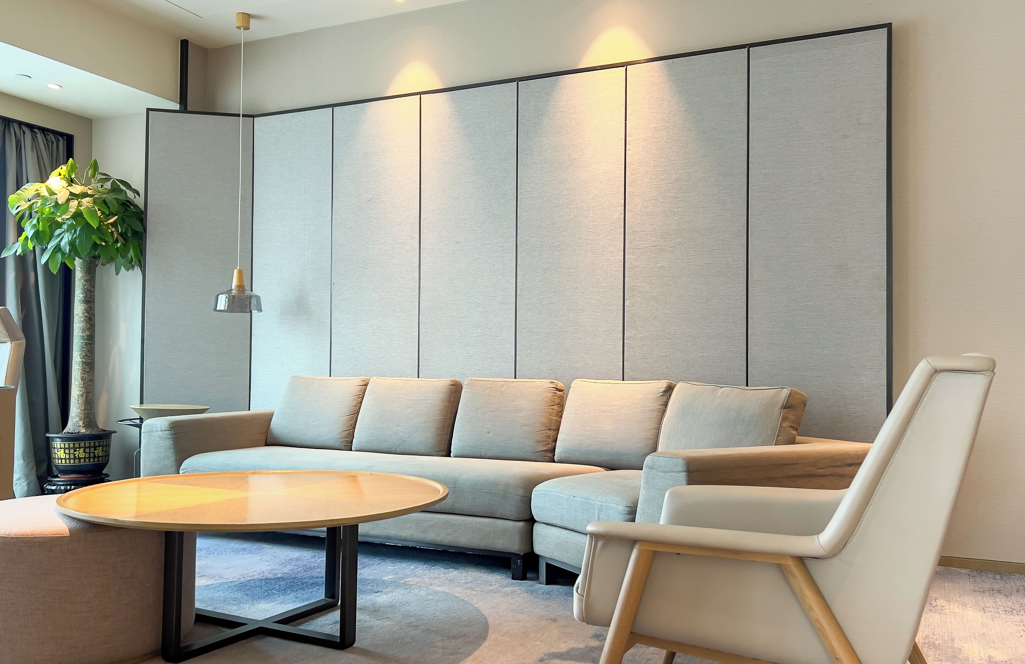 A modern living room with a sectional sofa, a round coffee table, and a white armchair.