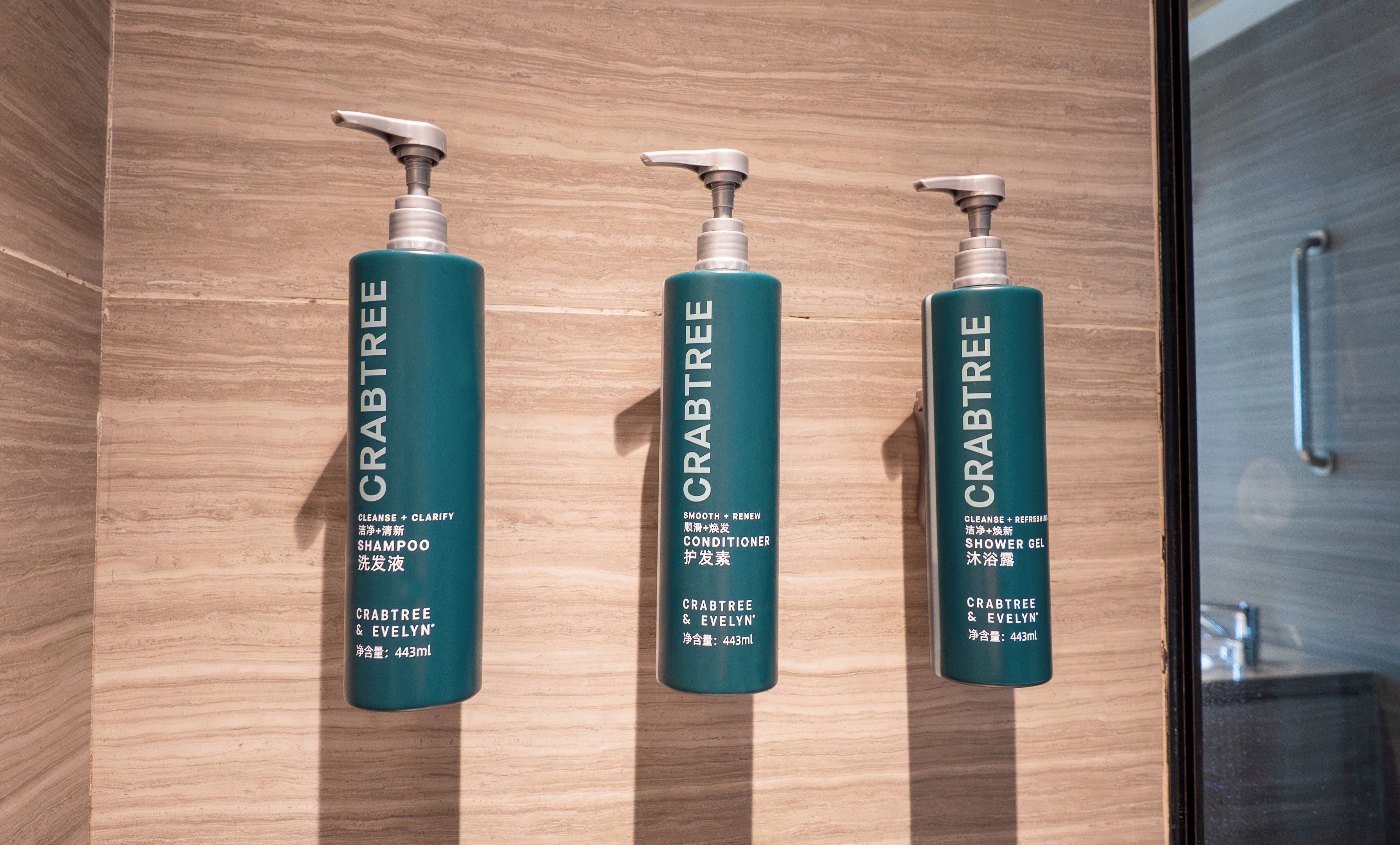 Three bottles of Crabtree & Evelyn products on a wooden surface.