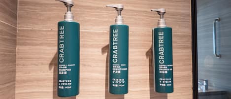 Three bottles of Crabtree & Evelyn products on a wooden surface.