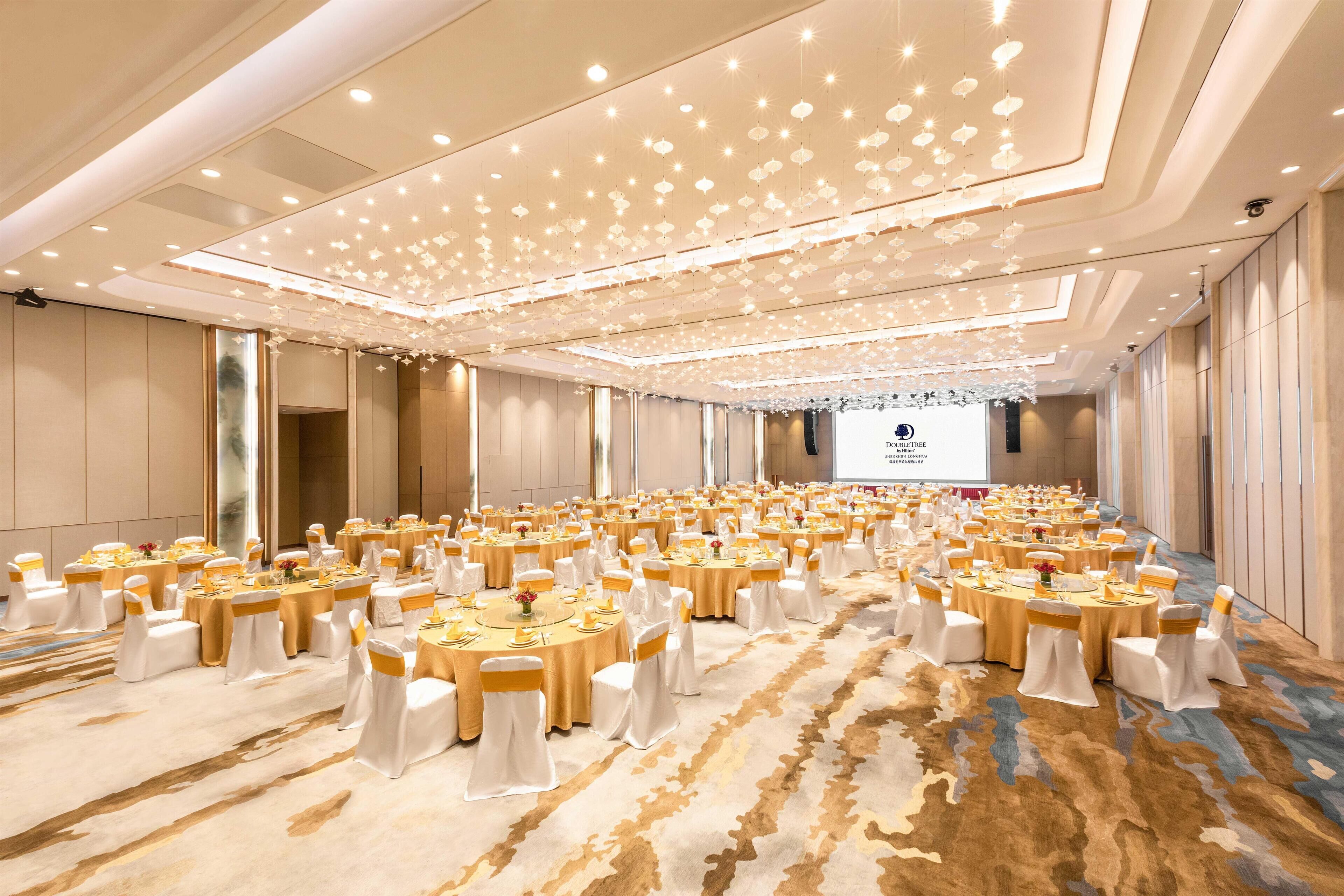 A large conference room with round tables, white chairs, and a carpeted floor.
