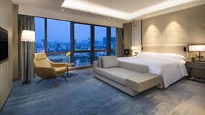Una habitación de hotel moderna con una cama grande, un sofá, una silla y un televisor.