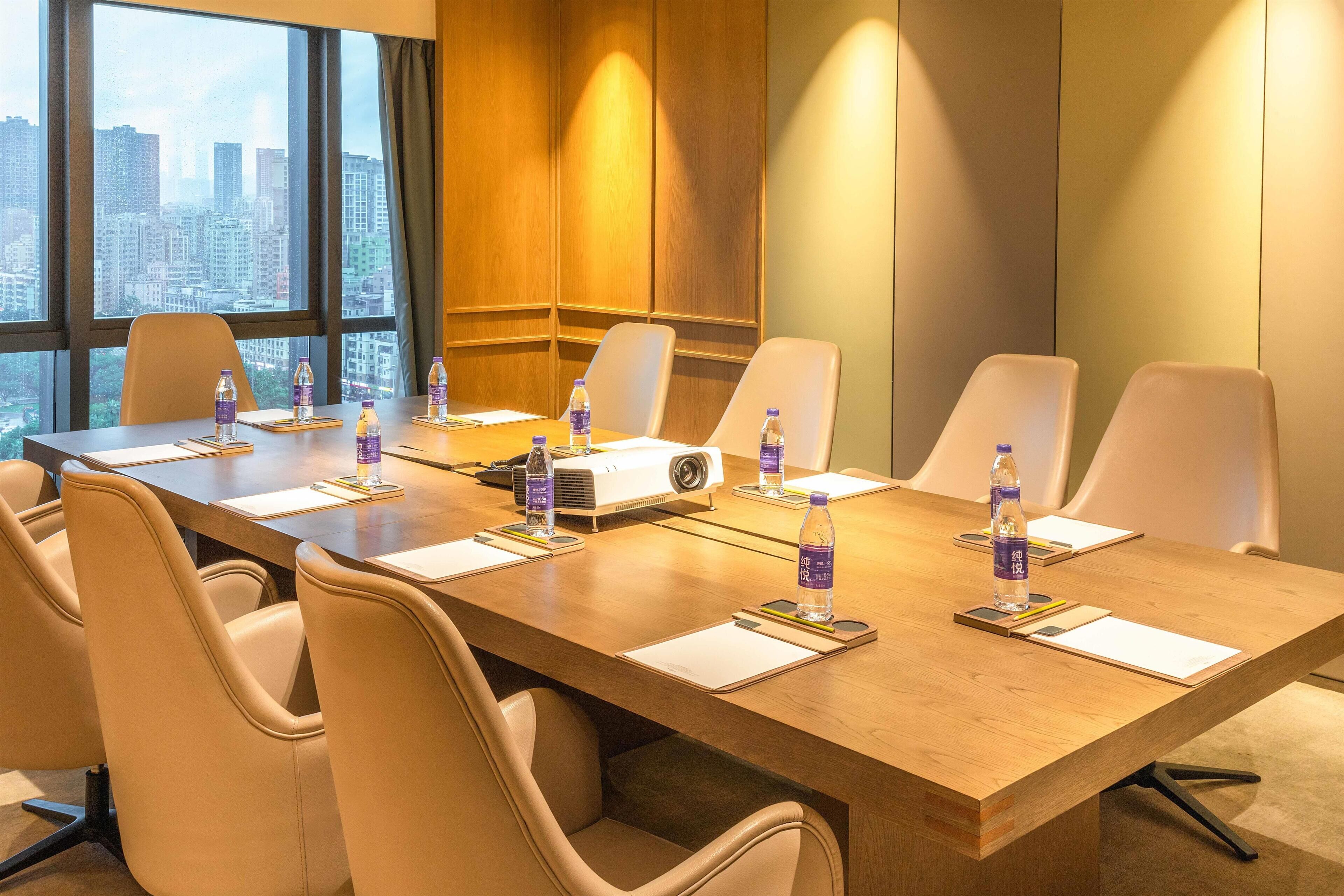 A conference room with a long table, chairs, a projector, and water bottles.