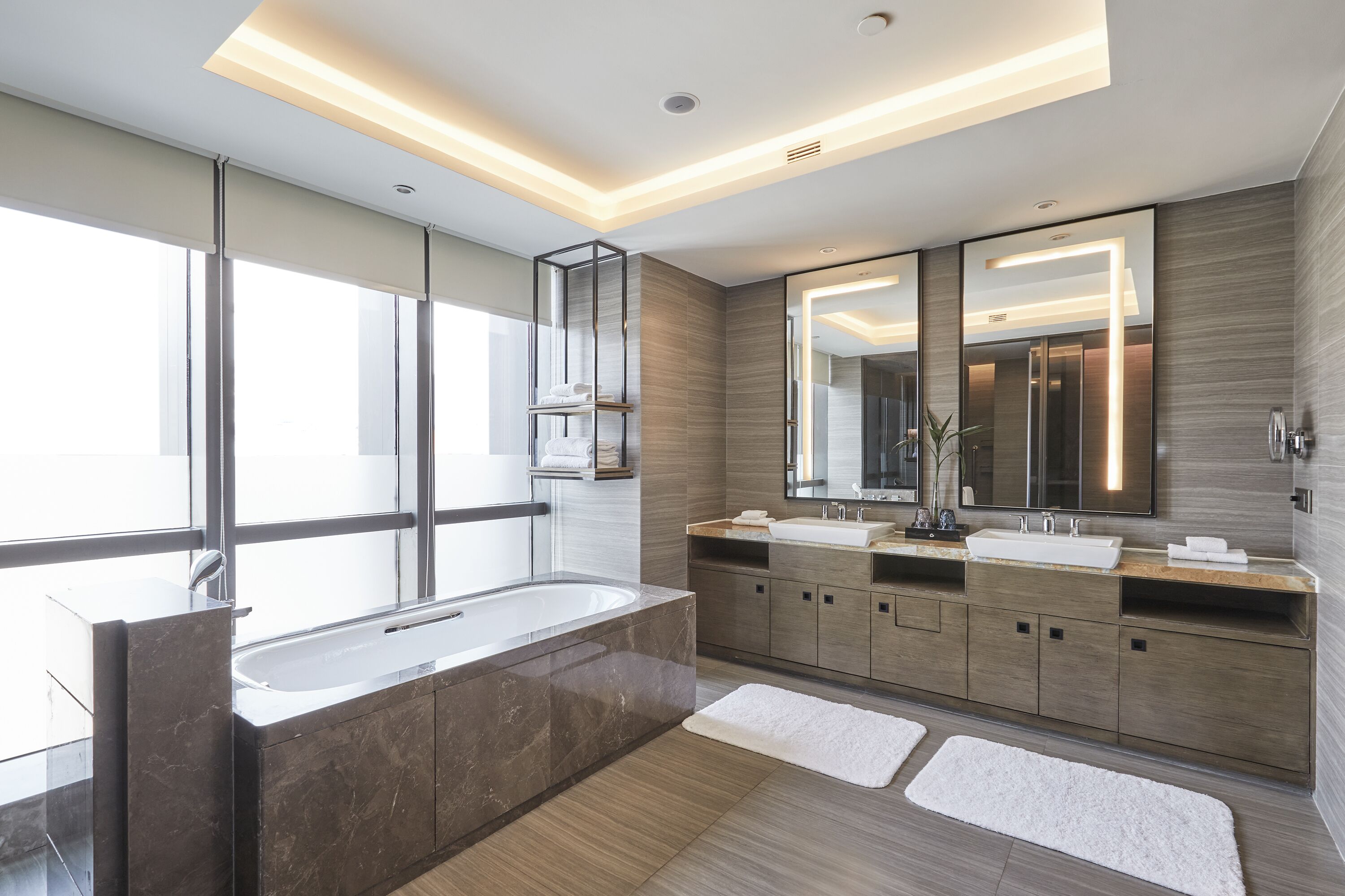 A modern bathroom with a large bathtub, dual sinks, and a large mirror.