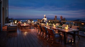 A wooden deck with a dining area, outdoor furniture, and a chef preparing food. - Grand Hyatt Sanya Haitang Bay Resort and Spa (Sanya)