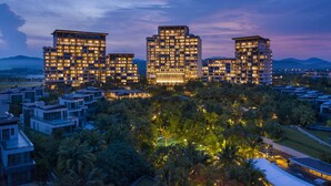 A modern hotel complex with multiple high-rise buildings, surrounded by lush greenery and a mountainous backdrop. - Grand Hyatt Sanya Haitang Bay Resort and Spa (Sanya)