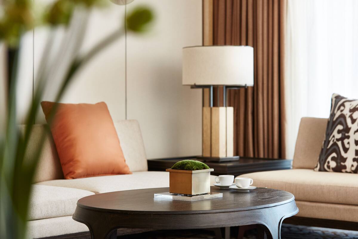 A modern living room with a round coffee table, a sofa with cushions, a lamp, and a small potted plant.