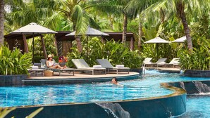 A pool area with lounge chairs, umbrellas, and a waterfall feature. - Grand Hyatt Sanya Haitang Bay Resort and Spa (Sanya)