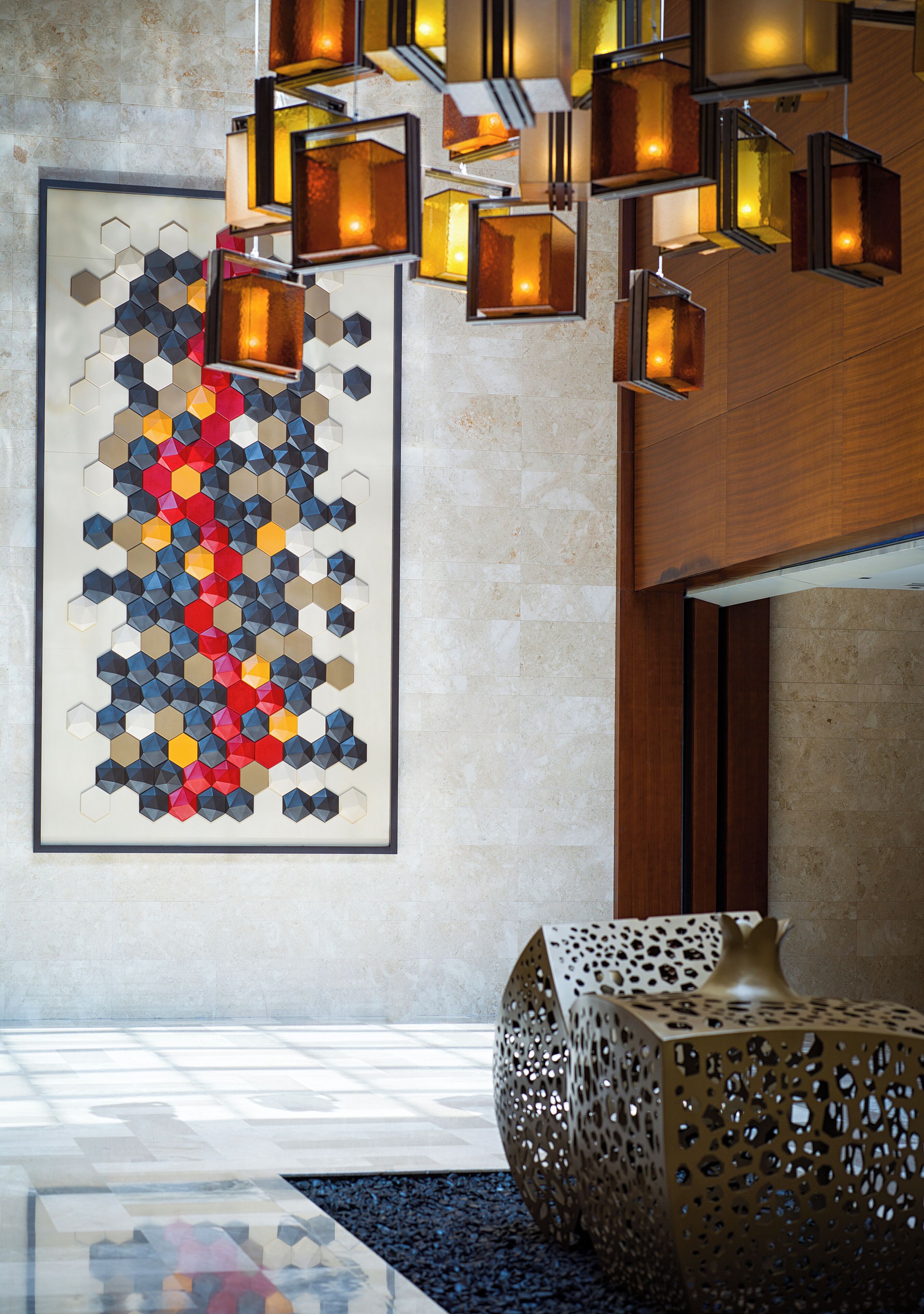 A modern lobby with geometric wall art, recessed lighting, and a decorative metal table.