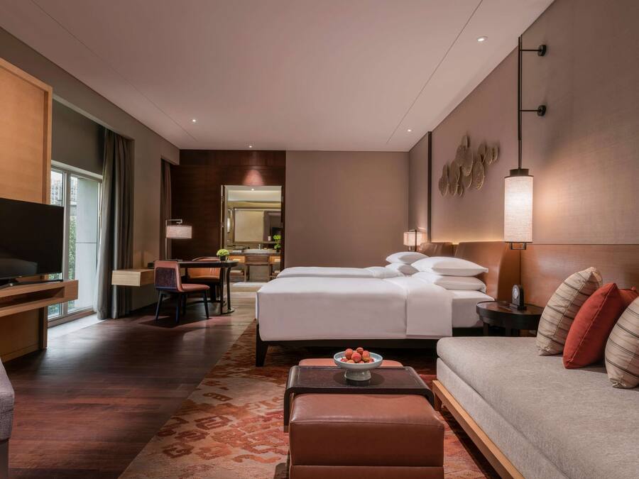 Habitació d'hotel moderna amb un llit gran, un sofà, una televisió i un escriptori.