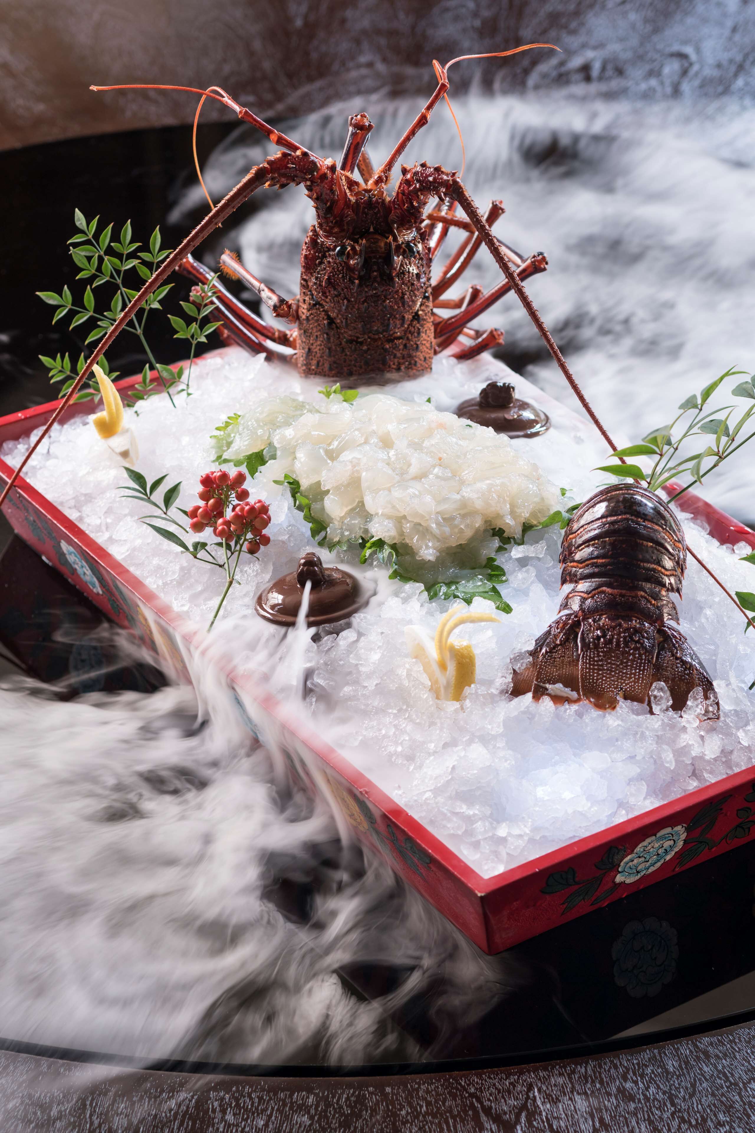 A lobster on ice with garnishes and a decorative box.