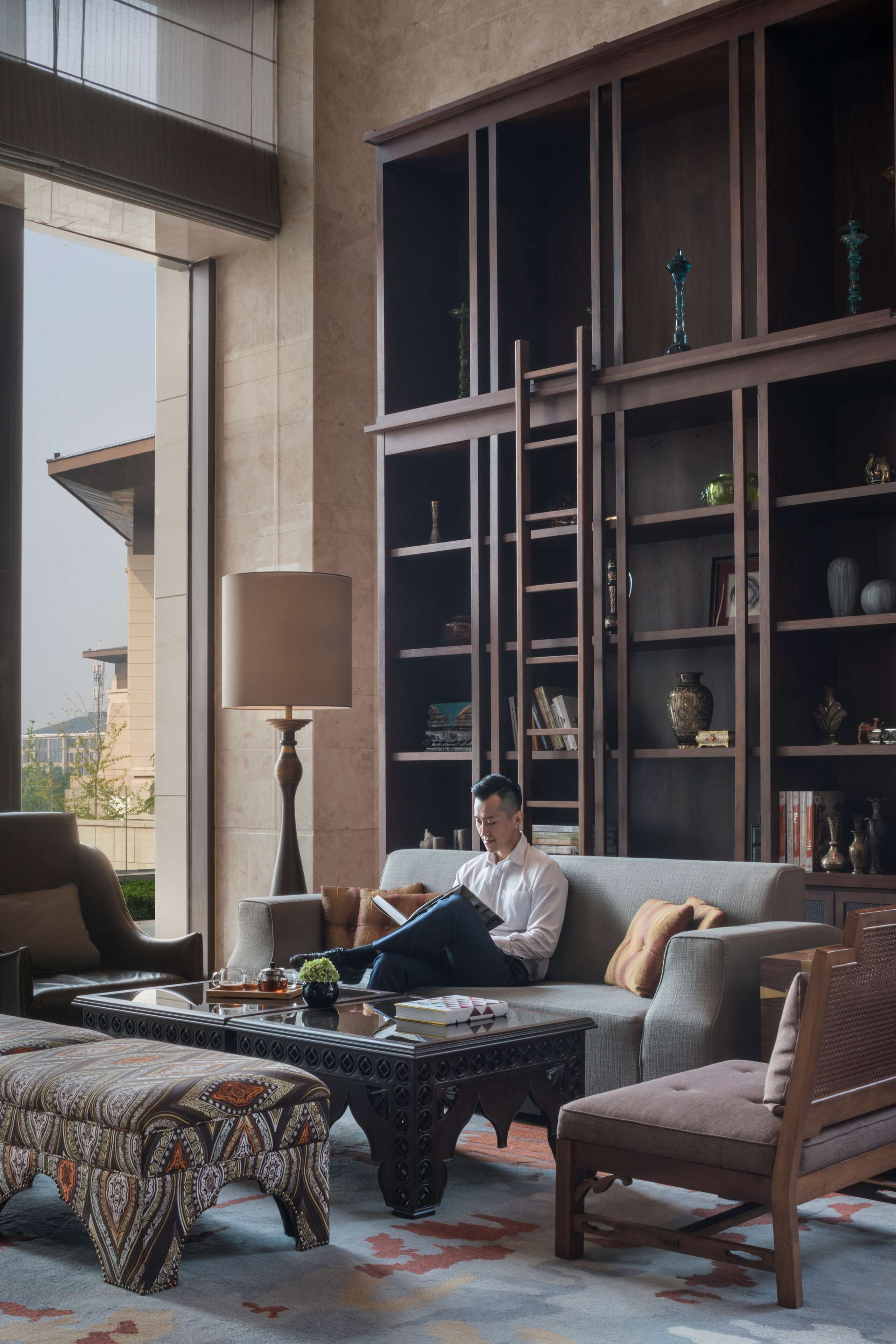 A modern living room with a sofa, armchair, coffee table, and a bookshelf.